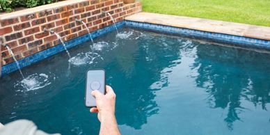 Person controlling a pool water feature using a smartphone app.