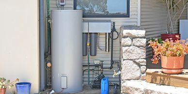 Outdoor water filtration and heating system setup on a house exterior wall.