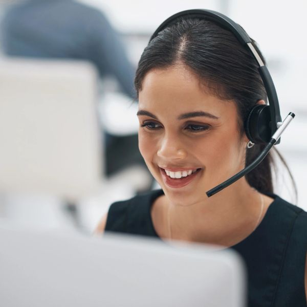 Smiling woman with headset working at computer.