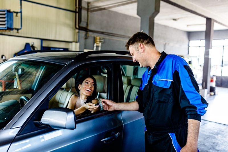 Young Salesman is Giving Car Keys to a Young Businesswoman After he had Repaired her Car.