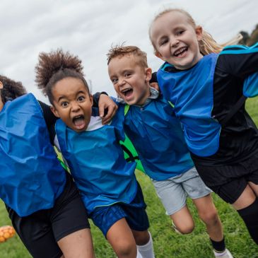 Happy kids in blue sports bibs posing together outdoors.
