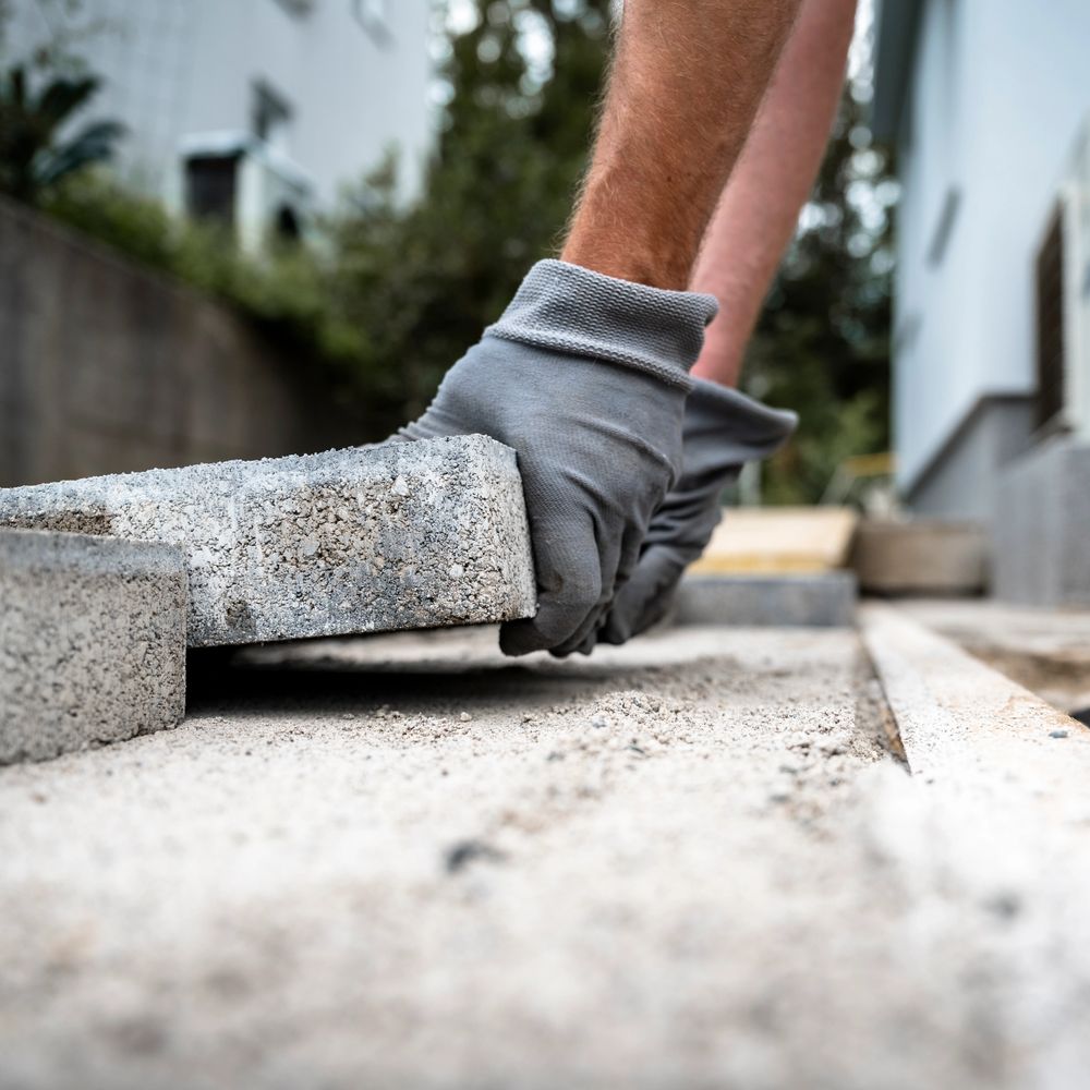 Worker wearing gloves laying concrete blocks for construction.