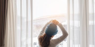 Woman stretching near a sunlit window.