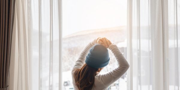 Person stretching in front of a window with curtains.