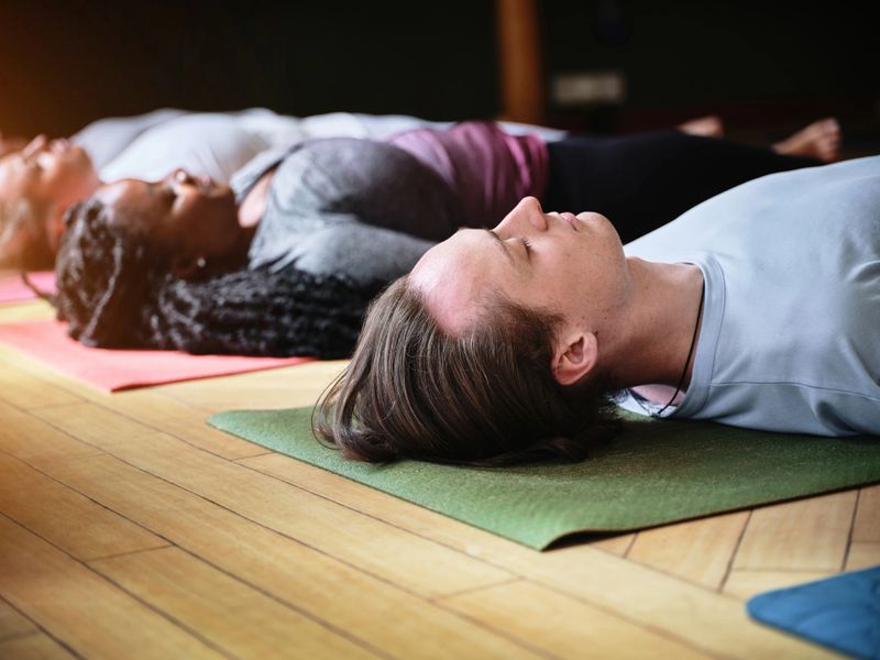 Yoga, floor and mediation to relax, people and fitness or calm, spiritual awareness and savasana. Class, resting and zen or holistic, peace and breathing for health, healing and self care or chakra