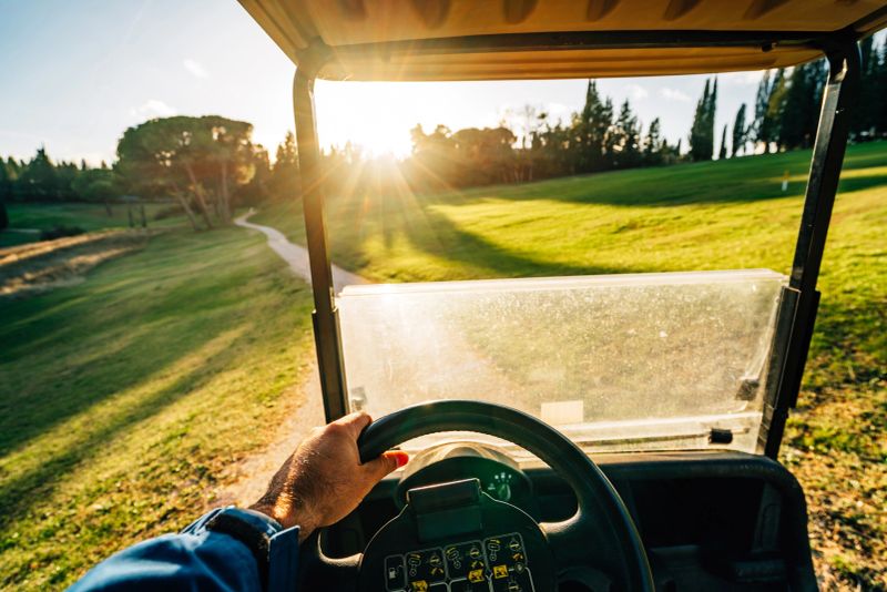 Pov view of a man driving a golf cart at sunset. Driving on the golf course.
