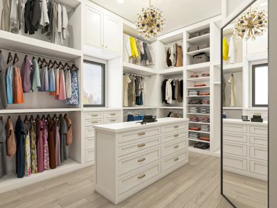 Spacious white walk-in closet with organized clothing and island drawer.