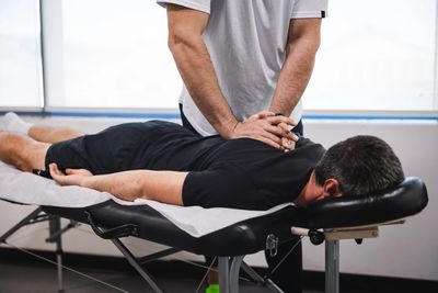  A chiropractor adjusting a patient in the mid-back.