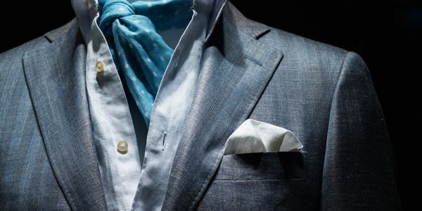 Close-up of a man wearing a gray suit, white shirt, and blue scarf.