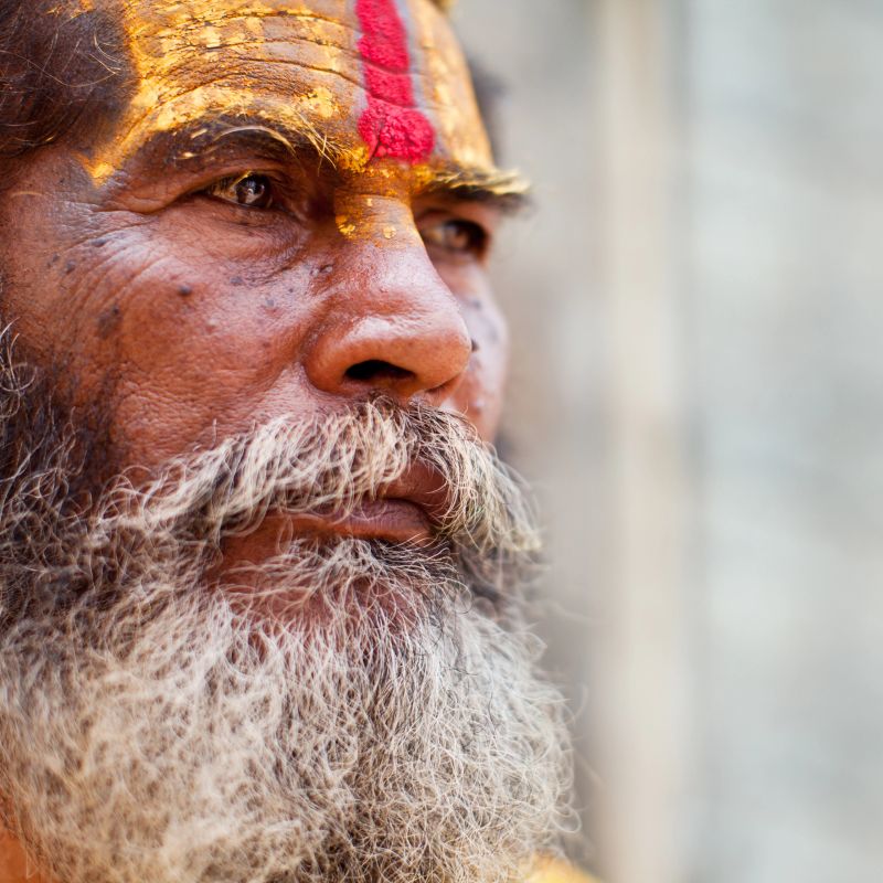 "Portrait of Holy Sadhu man with long beard and traditional face paint in Pashupatinath Temple, Kathamandu, Nepal."