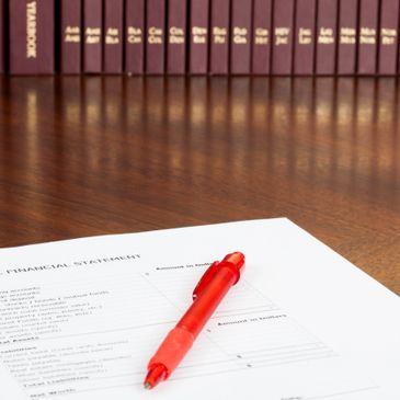 Red pen on a financial statement document on a wooden desk.