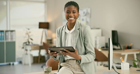Confident woman holding tablet and smiling in a modern office.