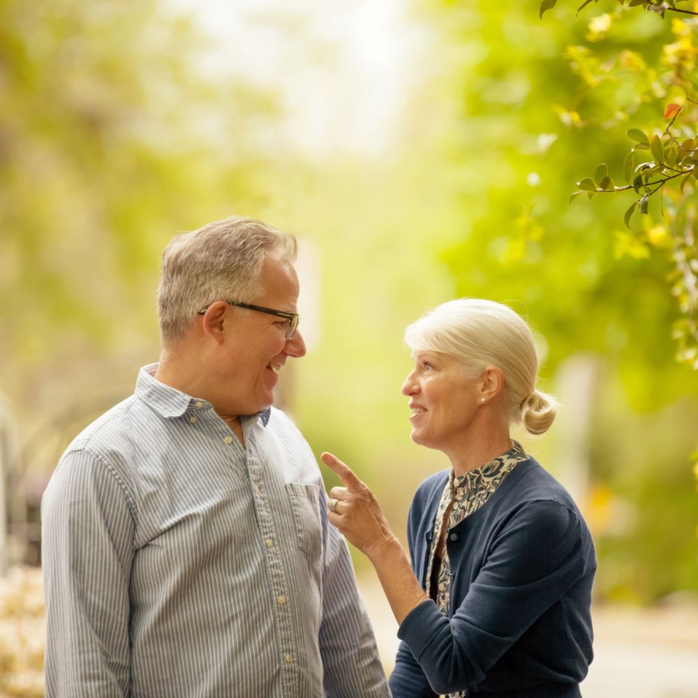 Older couple sharing a happy moment outdoors in a green setting.