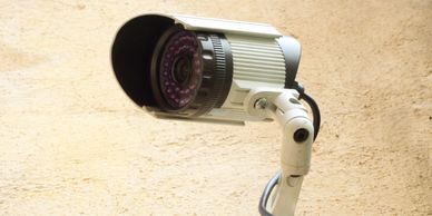 Close-up of a security camera mounted on a textured beige wall.