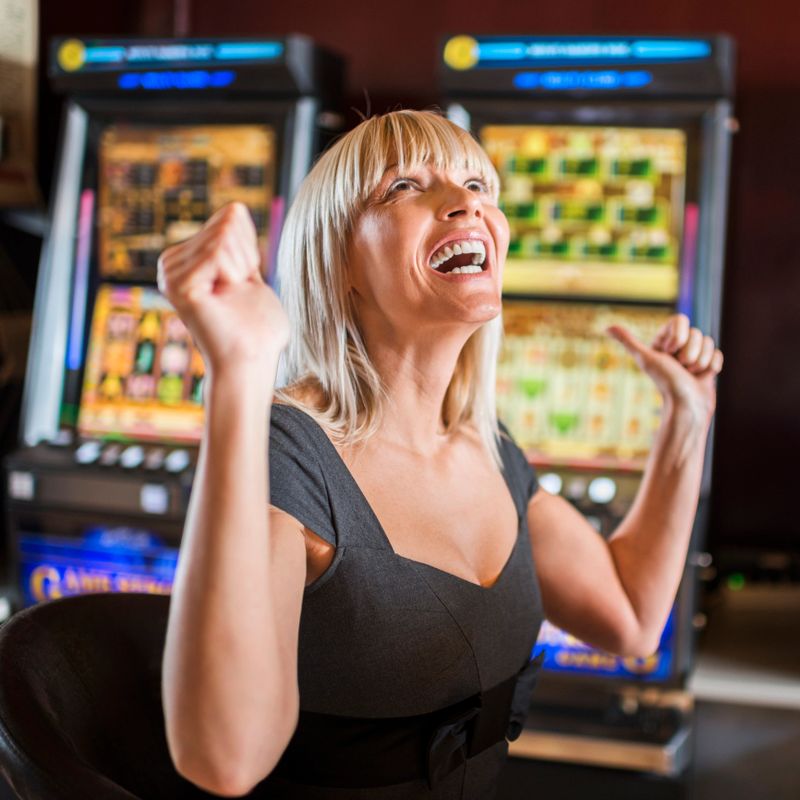 Ecstatic woman winning money on a slot machine in a casino.