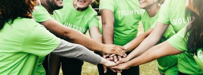 Group of volunteers stacking hands in unity.