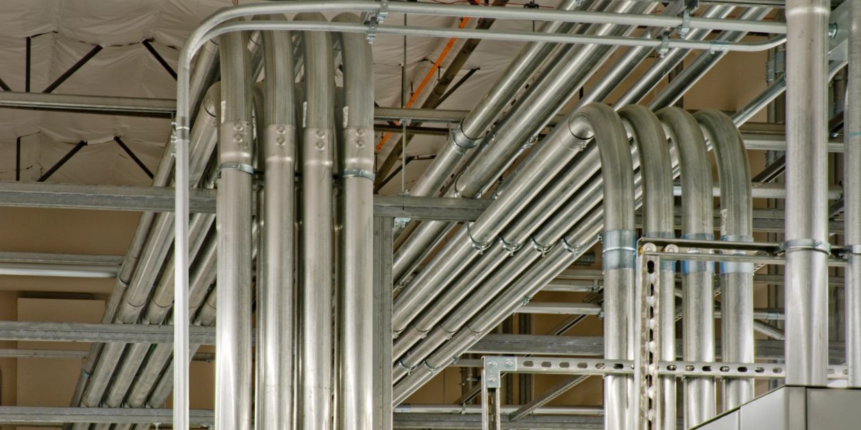 Industrial metal pipes and conduits running across ceiling.