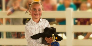Girl holding award-winning lamb at a fair.