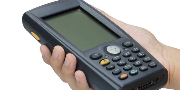 Hand holding a handheld electronic device with a screen and keypad.