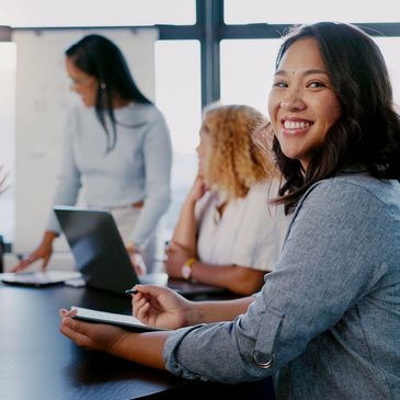 A confident woman smiles during a team meeting in a bright office.