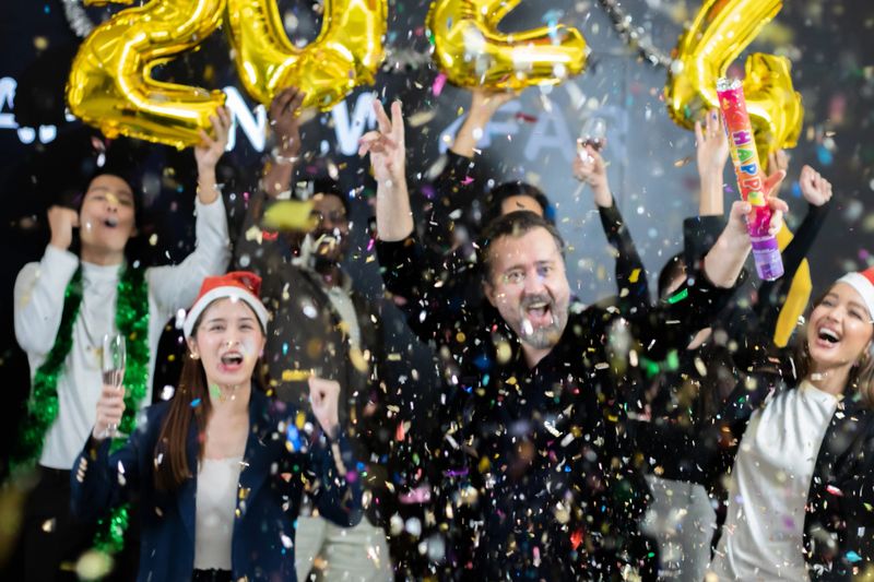 Group of happy multi-faith young people and female college student friends having fun and having fun celebrating holidays, meeting, dancing parties, and playing paper together in a room.