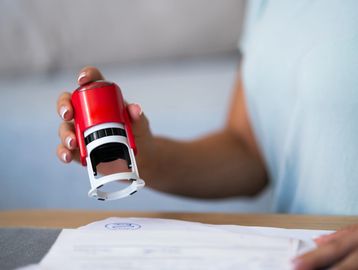 Person using a red stamp on a document.