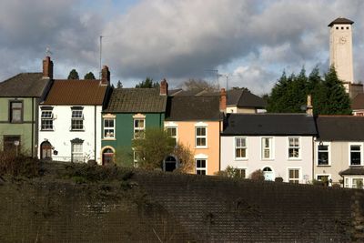 Row of colorful houses behind a brick wall under a cloudy sky.