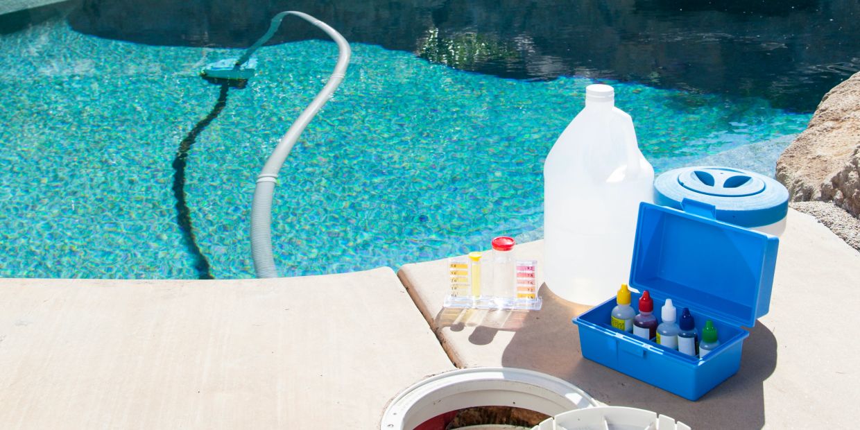 Pool cleaning tools and chemicals by a clear swimming pool.