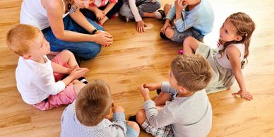 children and teacher sitting in a circle 