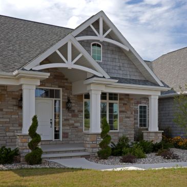 Modern house with stone facade and white pillars.