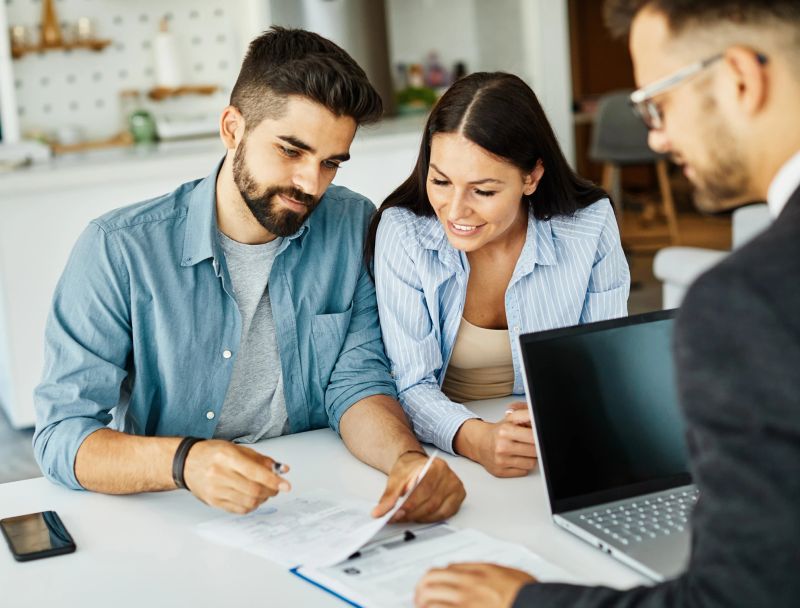 Real estate agent with couple shaking hands closing a deal and signing a contract