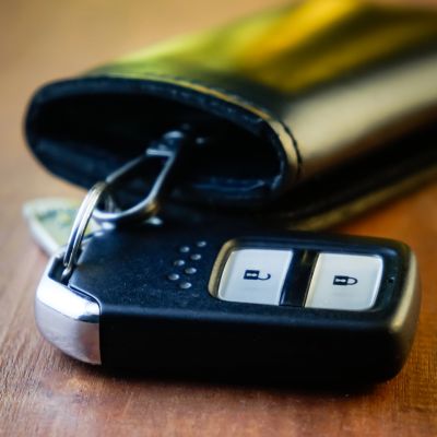 Car key fob and wallet on a wooden surface.