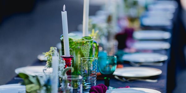 Elegant outdoor dining table set with candles and colorful glassware.
