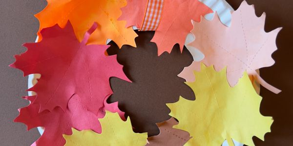Colorful paper autumn leaves arranged on a brown surface.