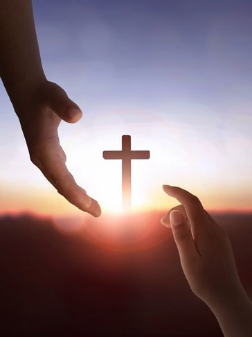Two hands reaching towards a cross at sunrise, symbolizing faith and hope.