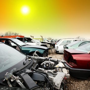 A junkyard filled with damaged and dismantled cars under a bright yellow sky.