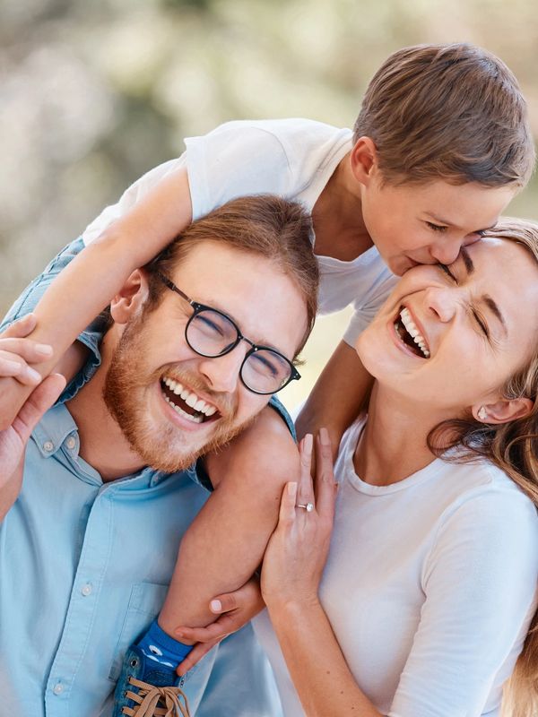 Happy family sharing joyful moment outdoors with child kissing mother.