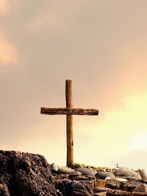 A wooden cross silhouetted against a glowing sunset sky.