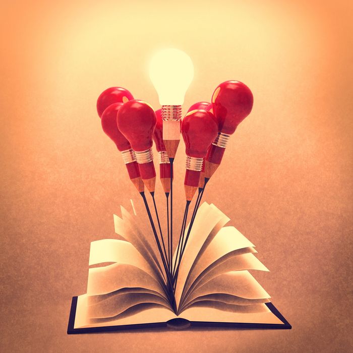 Open book with pencils shaped like light bulbs, one glowing brightly.
