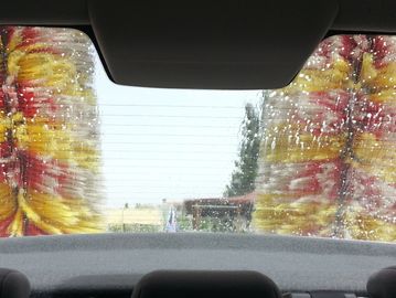 View through a car windshield during a car wash with spinning brushes.