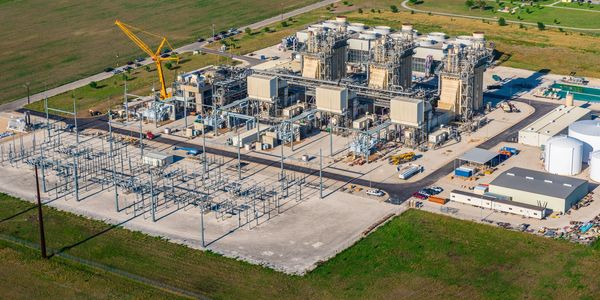 A large industrial power plant facility with multiple generators and a crane.