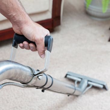 Hand holding a vacuum cleaner handle on carpet.