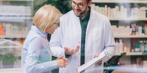 Farmacéutico asesorando a una cliente en la farmacia.