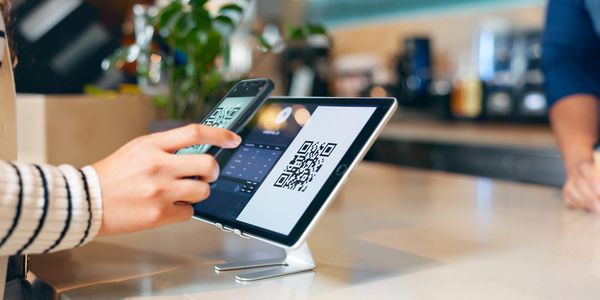 Person scanning a QR code on a tablet using a smartphone.