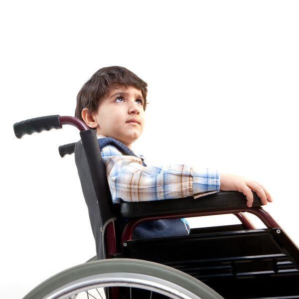 Young boy sitting in a wheelchair looking thoughtfully upward.