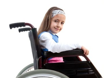 A young girl sitting in a wheelchair smiling gently.
