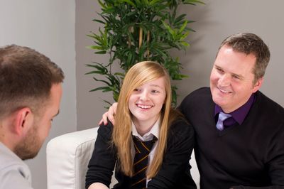 Father and daughter smiling during a meeting with a professional.