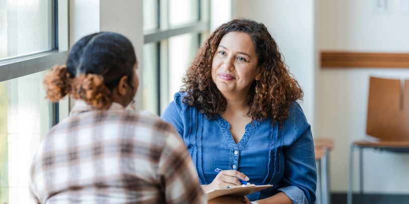 A woman attentively listens to another woman during a counseling session.