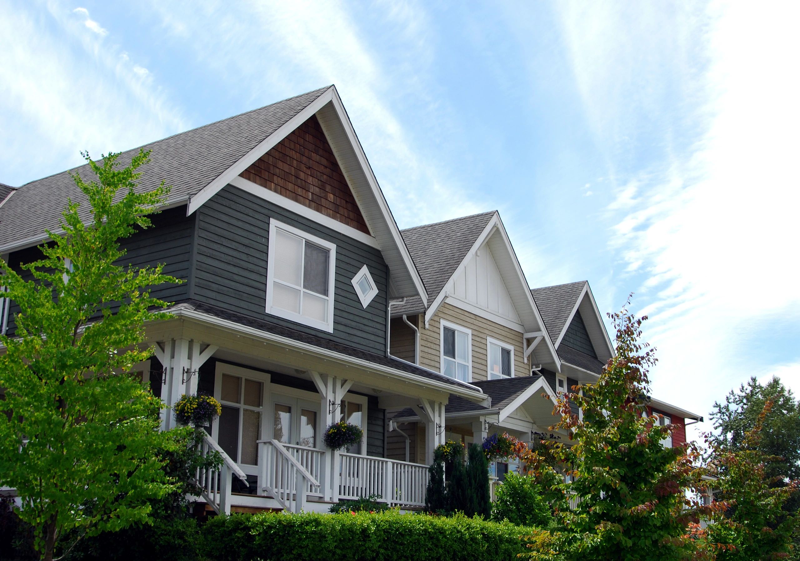 Row of colorful townhouses with blue sky and greenery.