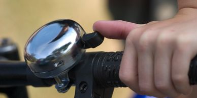 Hand pressing a bicycle bell on the handlebar.